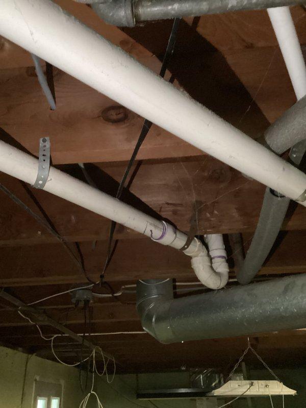 Responded to service call regarding suspected metal debris on bathtub floor originating from drain area. Performed visual inspection of tub drain assembly and surrounding plumbing fixtures, including chrome drain components and tub spout. Assessed basement plumbing infrastructure including PVC drainage lines, support strapping, and pipe connections to identify potential source of metallic material. Documented conditions with photographic evidence showing bathtub interior with chrome fixtures and exposed ceiling plumbing system. No immediate drain corrosion or structural failure observed during inspection.