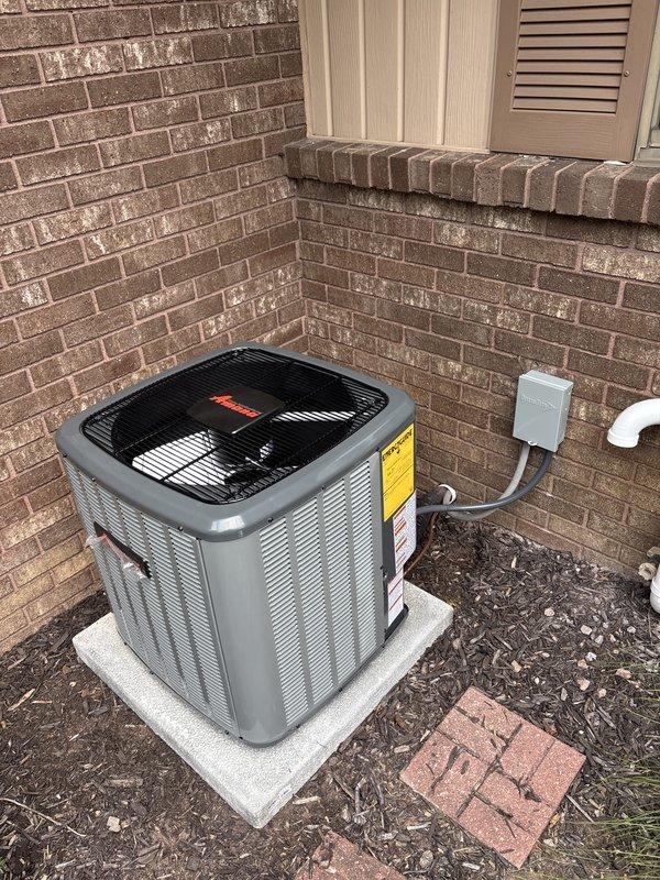 Completed full HVAC system installation including Bryant brand furnace and air conditioning condenser unit. Interior furnace installation in basement utility area included proper positioning on protective pad, connection of metallic flex ductwork, rigid supply ductwork, white PVC condensate drainage and venting lines, wall-mounted thermostat with associated wiring, and integration with existing sheet metal air handler component. Exterior condenser unit installed on concrete pad in brick alcove with proper electrical disconnect box mounting, conduit runs, and refrigerant line connections. All equipment positioned for adequate airflow clearance and maintenance access, system tested and verified operational.