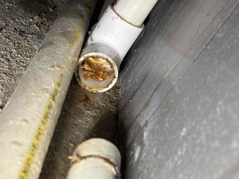 Responded to water leak at furnace base occurring during AC operation. Upon inspection, discovered condensate drain line completely clogged with sediment and debris buildup. The PVC drain pipe showed significant accumulation of rust-colored material blocking proper drainage flow. Cleared blockage from condensate drain system and verified proper water flow. Advised that AC unit can be safely operated now that drainage system is functioning correctly.