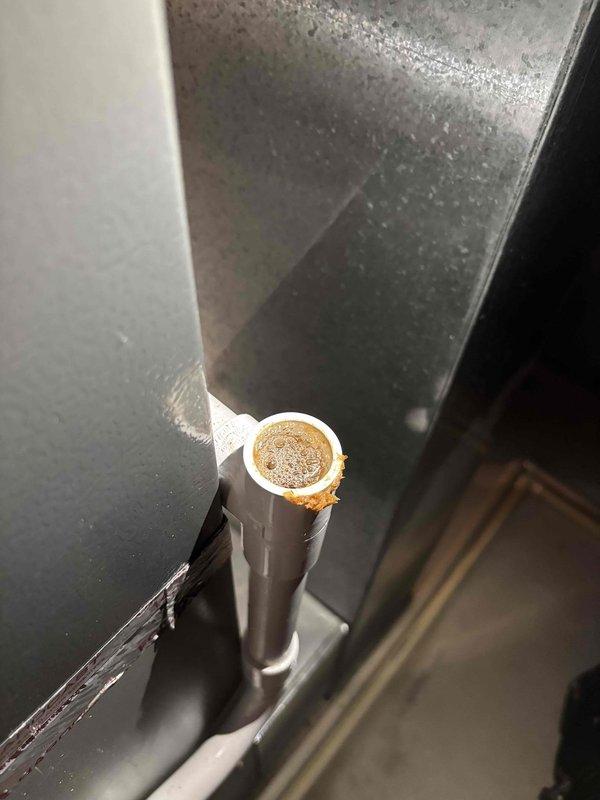 Responded to water leak at furnace base occurring during AC operation. Upon inspection, discovered condensate drain line completely clogged with sediment and debris buildup. The PVC drain pipe showed significant accumulation of rust-colored material blocking proper drainage flow. Cleared blockage from condensate drain system and verified proper water flow. Advised that AC unit can be safely operated now that drainage system is functioning correctly.