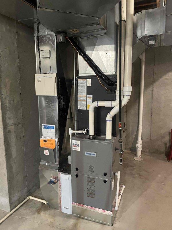 Completed full system replacement of residential HVAC equipment and water heater. Removed existing furnace, air handler, outdoor condenser unit, and water heater. Installed new gray metal furnace unit with black air handler/evaporator coil assembly in basement mechanical room. Mounted equipment vertically with proper spacing and clearances per manufacturer specifications. Connected white PVC drainage and venting pipes with appropriate routing. Installed black flexible ductwork from air handler to existing duct system. Connected metal supply ductwork and verified proper airflow pathways. Mounted electrical panel and completed all power connections with proper disconnects. Positioned new outdoor condenser unit on existing concrete pad with gravel surround adjacent to house exterior. Installed electrical conduit from wall-mounted disconnect box to condenser unit. Verified proper clearances around outdoor unit for airflow and future maintenance access. Completed all refrigerant line connec
