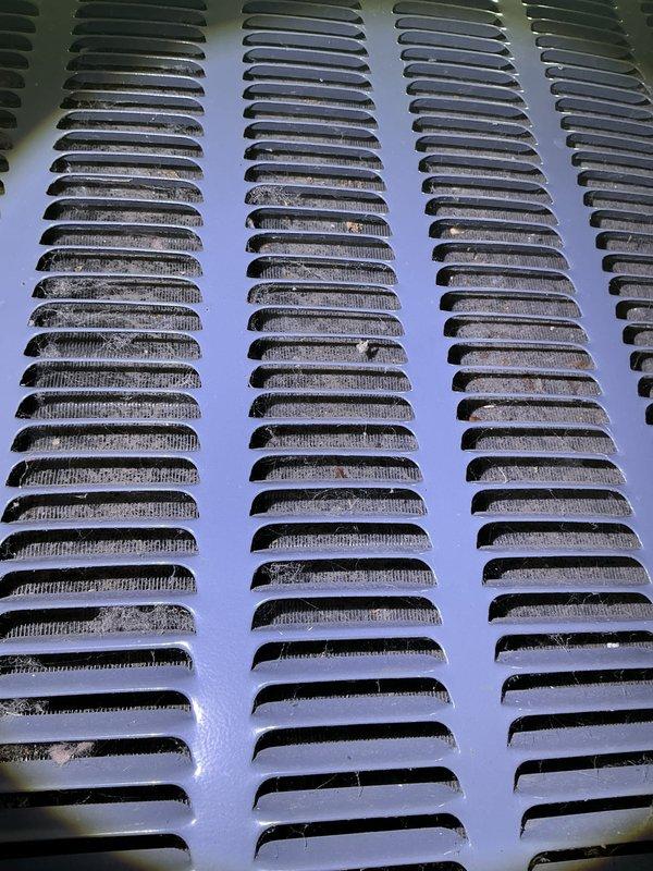 Completed annual cooling maintenance on heat pump system including comprehensive tune-up and filter replacement. Addressed ventilation grille with significant dirt, dust accumulation, and discoloration across multiple louvered columns. Documented existing condition showing brownish staining and debris buildup in vent openings and recessed areas, indicating extended exposure to environmental elements without recent cleaning.