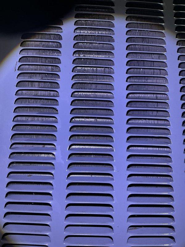 Completed annual cooling maintenance on heat pump system including comprehensive tune-up and filter replacement. Addressed ventilation grille with significant dirt, dust accumulation, and discoloration across multiple louvered columns. Documented existing condition showing brownish staining and debris buildup in vent openings and recessed areas, indicating extended exposure to environmental elements without recent cleaning.