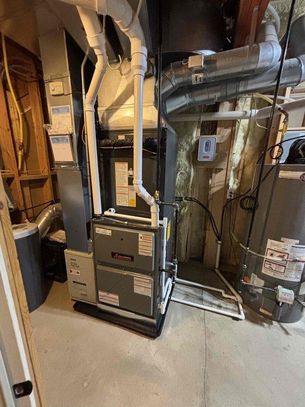 Complete HVAC system installation performed, including new furnace and air conditioning condenser unit. Furnace installed in basement utility area with proper PVC venting routed vertically through ceiling, integrated with existing ductwork system using metallic and flexible ducting. AC condenser unit positioned on exterior rock retaining wall against building with proper refrigerant line connections, electrical disconnect box mounted to siding, and all required electrical conduit installed. All equipment secured, tested, and verified operational per manufacturer specifications.