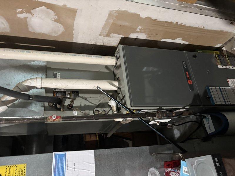 Completed annual cooling maintenance on 20-year-old Trane system. Performed comprehensive inspection of air handler unit and condensate drain assembly, documented system conditions with photos showing coil air return section and refrigerant line connections. All components operating within normal parameters at time of inspection.