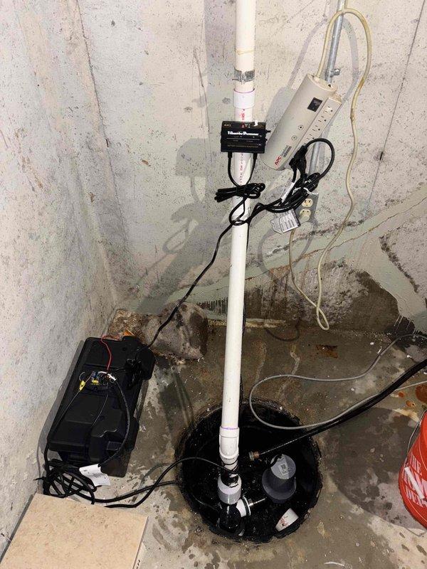 Completed installation of new main sump pump system with backup pump configuration in basement corner location. Repiped both primary and backup sump pump discharge lines due to improper existing configuration, installing new check valves throughout the system to prevent backflow. Replaced leaking section of 4" main drain piping with new PVC pipe and fittings, utilizing proper primer and solvent welding techniques for all connections. All work includes 1-year workmanship guarantee.