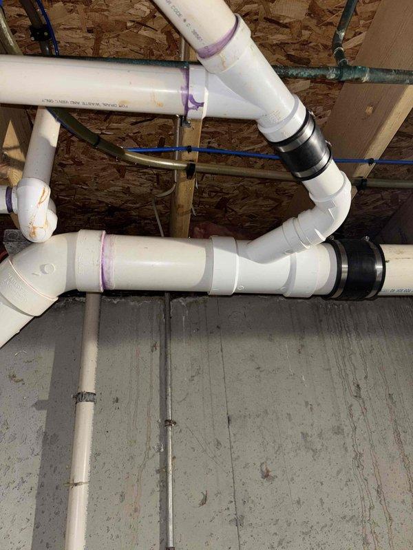 Completed installation of new main sump pump system with backup pump configuration in basement corner location. Repiped both primary and backup sump pump discharge lines due to improper existing configuration, installing new check valves throughout the system to prevent backflow. Replaced leaking section of 4" main drain piping with new PVC pipe and fittings, utilizing proper primer and solvent welding techniques for all connections. All work includes 1-year workmanship guarantee.
