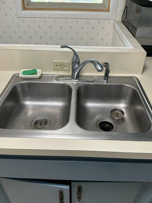 Installed new Insinkerator garbage disposal unit under kitchen sink in 1957-era home. Completed installation includes proper electrical connection via armored cable, PVC drain plumbing with P-trap assembly, and secure mounting to underside of countertop. Verified unit operates correctly with existing double-basin stainless steel sink and drain configuration. All connections tested and confirmed leak-free.