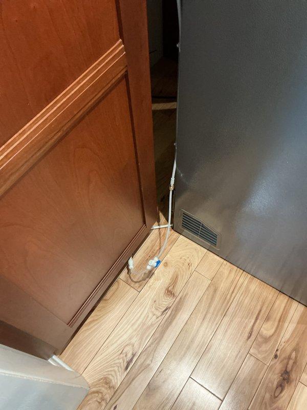 Completed refrigerant line connection for refrigeration unit. Routed copper lines through interior doorway corner, securing lines along baseboard area to ensure proper clearance and code compliance. Verified all connections were properly brazed and pressure-tested system for leaks before final commissioning.