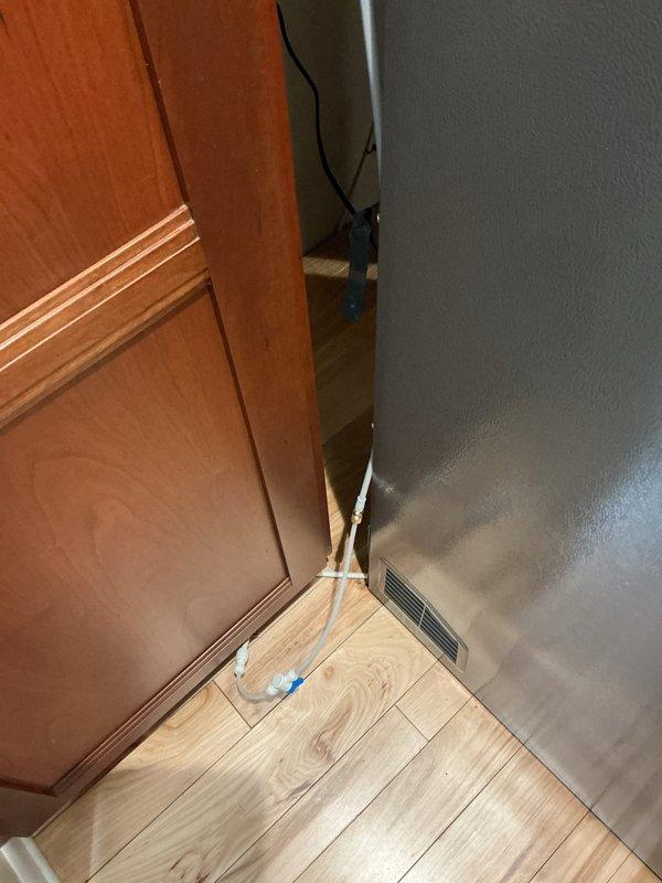 Completed refrigerant line connection for refrigeration unit. Routed copper lines through interior doorway corner, securing lines along baseboard area to ensure proper clearance and code compliance. Verified all connections were properly brazed and pressure-tested system for leaks before final commissioning.