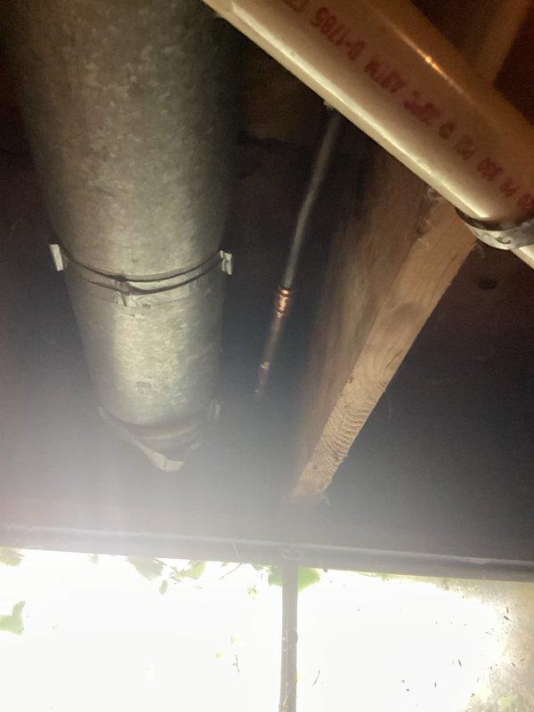 Responded to service call for low water pressure issue and frost-free faucet installation request. Upon arrival, inspected exterior plumbing connections and identified existing hose bibb penetration through building siding with vegetation growth around fixture area. Assessed current plumbing configuration including visible copper supply lines and galvanized ductwork in crawlspace or basement area beneath structure. Documented existing conditions showing weathered exterior siding, mounting hardware locations, and accessibility of plumbing penetrations for potential frost-free faucet installation points.