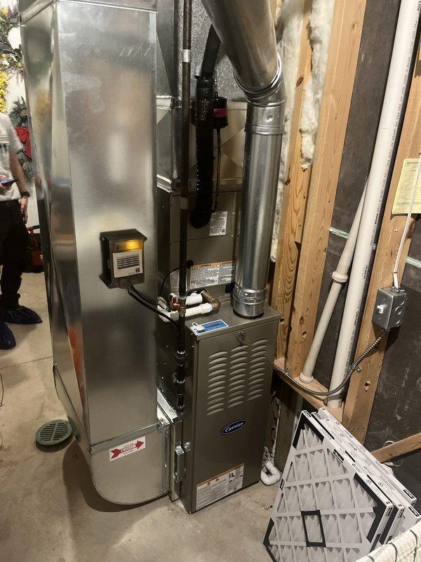 Completed full residential HVAC system installation in basement utility area, including new Carrier furnace unit and air conditioning system. Installed furnace with proper venting using white PVC piping, connected metallic ductwork and plenum assembly, and secured all connections with appropriate banding and clamps. Positioned equipment adjacent to existing water heater, ensuring proper clearances and access for future maintenance. Integrated electrical connections, mounted necessary controls, and verified all components were properly secured to wooden framing. Installation completed as same-day booking with all ductwork, refrigerant lines, and exhaust venting installed to manufacturer specifications.