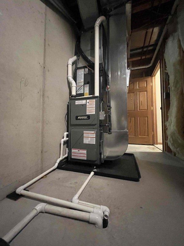 Completed full installation of Coleman furnace and air conditioning system in basement mechanical room. Installed new furnace unit on protective rubber mat with proper clearances, connected all necessary ductwork including vertical supply plenum and horizontal distribution system, and ran white PVC condensate drainage lines in U-trap configuration per code requirements. System tested and operational upon completion.