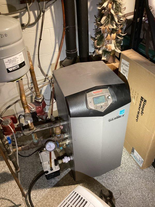 Responded to request for water heater replacement estimate at single family residence built in 1938. Upon arrival, assessed existing mechanical systems in basement utility area and documented current equipment configuration. Observed modern boiler system with Energy Star certification, extensive copper piping network with multiple valves and pressure gauge, expansion tank, and large blue pressure tank with associated plumbing connections. Photographed existing installation to provide comprehensive documentation for replacement estimate. Customer was not present during site visit as scheduled.