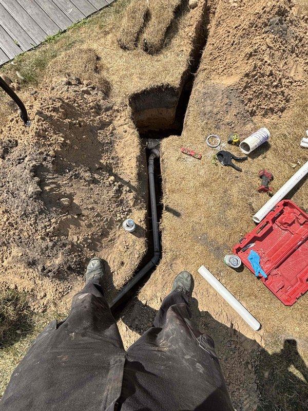 Completed kitchen sink drain line replacement requiring exterior excavation. Trenched from foundation to main drainage connection point, removed deteriorated drain piping, and installed new black drainage line with proper slope and fittings. Backfilled trench and restored work area upon completion of installation and testing.