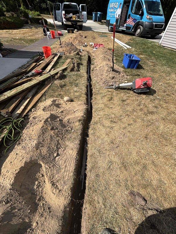 Completed kitchen sink drain line replacement requiring exterior excavation. Trenched from foundation to main drainage connection point, removed deteriorated drain piping, and installed new black drainage line with proper slope and fittings. Backfilled trench and restored work area upon completion of installation and testing.
