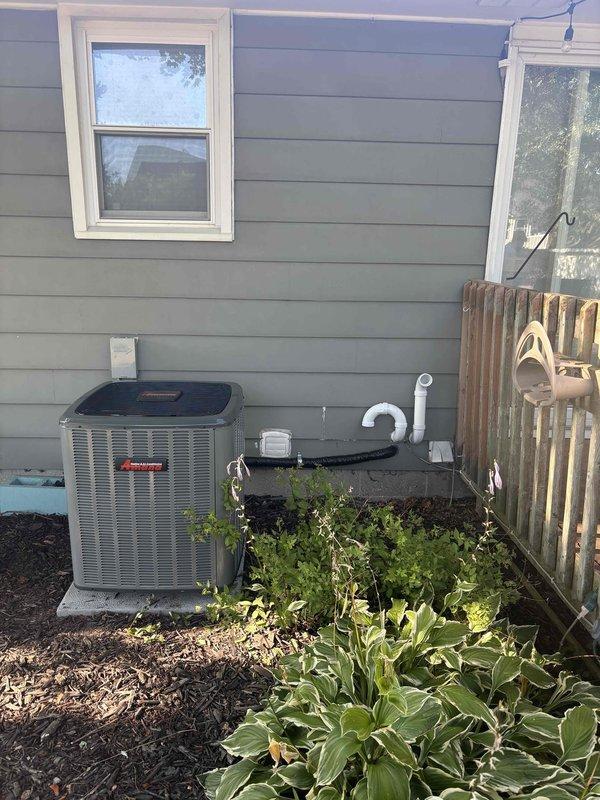 Completed full residential air conditioning system replacement with installation of new Amana condenser unit on exterior concrete pad. Unit positioned adjacent to building with proper clearances maintained from landscaping and structures. Established all refrigerant line connections, condensate drainage via PVC piping, and electrical service to new outdoor unit. Interior air handler integrated with existing ductwork system, with flexible duct connections secured and all ventilation components properly configured. Verified system startup, refrigerant charge levels, and operational parameters across all equipment. All connections tested and confirmed leak-free with system cycling properly through cooling modes.