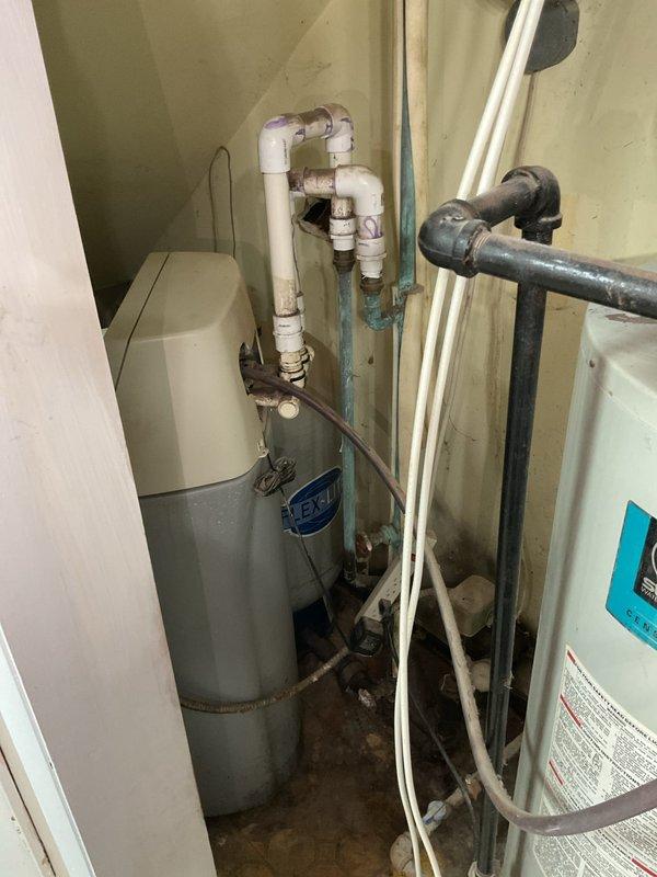 # Water Softener and Water Heater System Evaluation

Conducted comprehensive on-site evaluation of existing water softener and water heater installation in utility closet. Assessed current plumbing configuration, including water heater with overhead PVC piping network, adjacent HVAC air handler unit, and associated water supply lines with braided flex connections. Documented mechanical space layout showing aged galvanized ductwork, copper piping, various shutoff valves including red-handled valve, and complex pipe routing throughout confined vertical space. Photographed existing conditions including water heater with visible manufacturer identification, floor staining indicating potential previous moisture issues, and overall system integration within the mechanical room. Evaluated feasibility of water softener installation considering space constraints and existing plumbing infrastructure. Provided recommendations for system modifications and equipment placement options based on curre