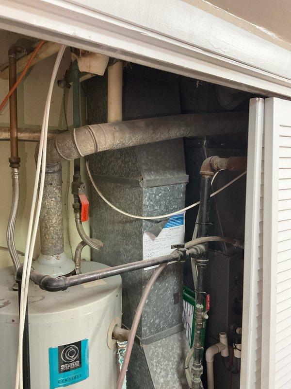 # Water Softener and Water Heater System Evaluation

Conducted comprehensive on-site evaluation of existing water softener and water heater installation in utility closet. Assessed current plumbing configuration, including water heater with overhead PVC piping network, adjacent HVAC air handler unit, and associated water supply lines with braided flex connections. Documented mechanical space layout showing aged galvanized ductwork, copper piping, various shutoff valves including red-handled valve, and complex pipe routing throughout confined vertical space. Photographed existing conditions including water heater with visible manufacturer identification, floor staining indicating potential previous moisture issues, and overall system integration within the mechanical room. Evaluated feasibility of water softener installation considering space constraints and existing plumbing infrastructure. Provided recommendations for system modifications and equipment placement options based on curre