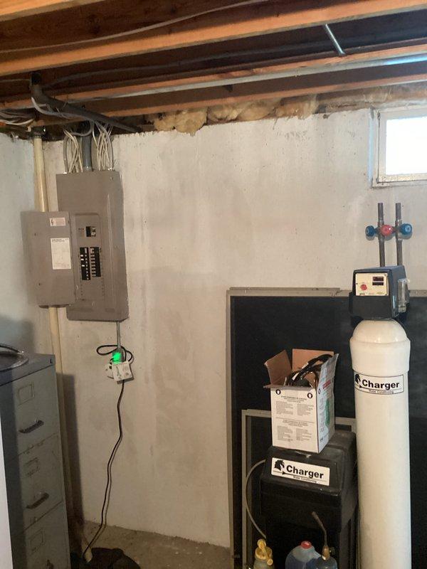 Conducted on-site evaluation for whole-house Generac generator installation at a residence built in 1985 with no existing backup power system. Assessed basement electrical infrastructure, including main service panel with circuit breakers and subpanel configuration, to determine optimal installation approach and required electrical upgrades. Documented existing 200-amp electrical service, panel capacity, and available space for generator transfer switch installation. Evaluated exterior placement options for generator unit considering gas line access, clearance requirements, and local code compliance. Photographed electrical panel layout, conduit routing, and basement utility area to support equipment sizing and installation planning. No safety concerns identified during assessment.