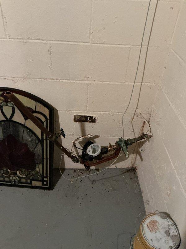 Responded to vandalized property with severed main water line and disconnected water heater. Assessed damage to plumbing infrastructure including cut water supply line and compromised water heater connections. Documented exposed plumbing assembly with valve mechanism showing corrosion and aging components, along with green pipe fittings and wall penetration. Inspected water heater with intact ventilation ductwork and brass fittings, though unit was disconnected from water supply. Photographed all affected areas for documentation purposes. Enrolled property in club membership program covering one furnace, one air conditioning unit, and one humidifier for ongoing maintenance services.