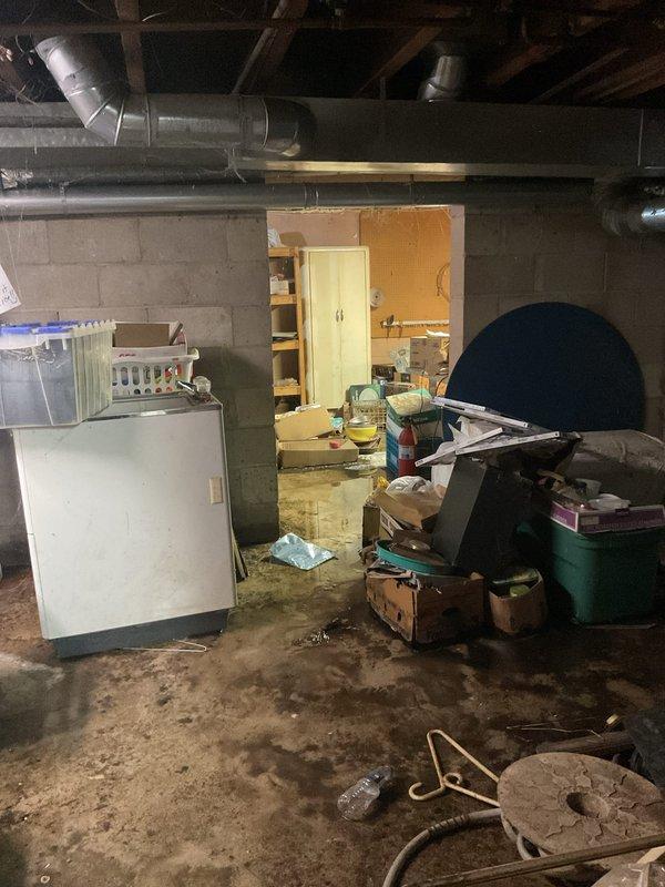 Responded to emergency service call for non-operational sump pump system. Upon arrival, found basement with standing water on concrete floor and sump pump present but not functioning. Inspected sump pump unit, discharge piping, and surrounding area which showed evidence of water intrusion and moisture damage to concrete block walls. Assessed system failure and water accumulation in basement space. Documented conditions including flooded floor area, sediment accumulation, and moisture-related wall deterioration with efflorescence present on block surfaces.