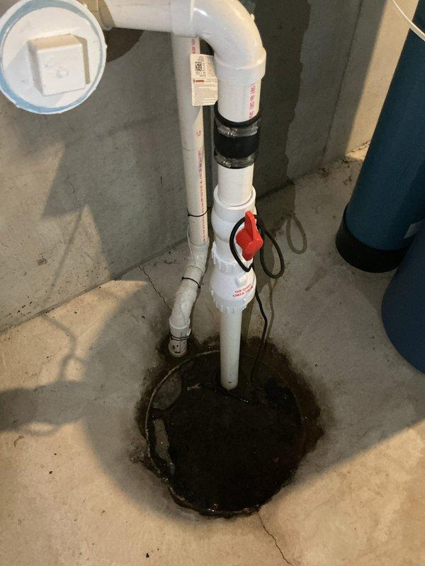 Responded to basement drain backup issue where bathroom drain was flowing upward. Assessed the drainage system and sump pump assembly, including the vertical PVC pipe configuration with shut-off valve and the floor drain opening. Cleared the clog in the basement drainage line, restoring proper flow direction and eliminating the backup condition.