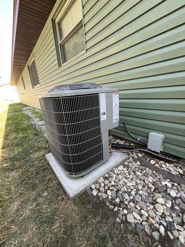 Successfully completed full air conditioning system replacement at residential property. Removed existing outdoor condensing unit and installed new unit on concrete pad with proper leveling and stabilization. Connected refrigerant lines with appropriate insulation, installed condensate drain line with PVC piping routed along exterior wall, and mounted electrical disconnect box per code requirements. Unit positioned on existing concrete pad surrounded by river rock landscaping for proper drainage and airflow clearance. Verified all electrical connections, tested system operation, and confirmed proper refrigerant charge and airflow through condenser fan assembly. Installation meets manufacturer specifications and local building codes.