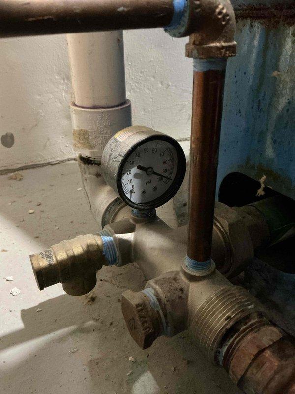 Responded to water heater leak on Bradford unit with warranty expiration date of September 2026. Upon inspection, confirmed active tank leak while unit continued to maintain heating functionality. Documented existing plumbing configuration including pressure relief valve assembly, brass fittings, and copper supply lines showing age-related wear and corrosion. Photographed installation conditions and basement utility area for warranty claim processing and recommended full tank replacement due to compromised tank integrity.