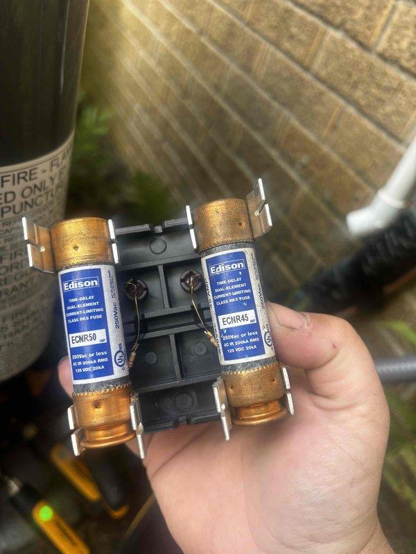 Completed annual cooling maintenance inspection on air conditioning system under warranty coverage expiring in 2036. During the tune-up, inspected and photographed the electrical disconnect fuse assembly, which contained two Edison brand time-delay dual-element current-limiting class RK5 fuses (ECNR50 and ECNR45 ratings) mounted in the fuse block, rated for 250VAC or less with 50kA interrupting capacity. All electrical components were found to be in proper working condition with no issues identified during the preventive maintenance visit.