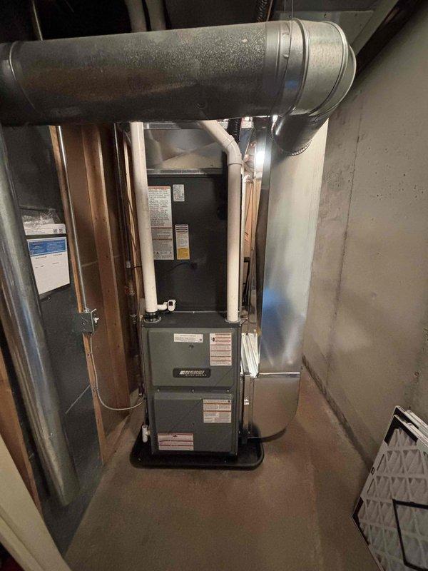 Completed full HVAC system installation including new furnace and air conditioning condenser unit. Installed furnace in basement utility area with proper clearances for maintenance access. Connected refrigerant lines, ductwork, and ventilation components. Mounted outdoor AC condenser unit on composite pad against exterior wall with proper clearance. Installed condensate drain line with white PVC piping along exterior wall. Verified all electrical connections, refrigerant line connections, and duct sealing. Installed new air filter in system. System tested and operational upon completion.