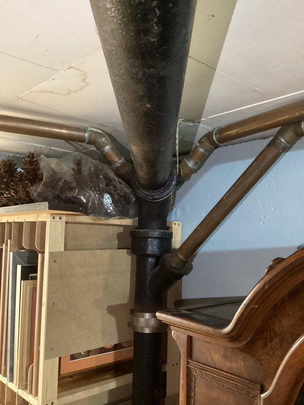 Performed comprehensive inspection of main sewer drain line in mid-1950s home previously converted from septic to city sewer system. Assessed visible rust and deterioration on vertical cast iron stack and associated drainage piping running from upper level fixtures down through basement to street connection. Documented condition of exposed plumbing infrastructure including corroded sections of main drain line, copper supply lines, and junction points. Photographed affected areas showing rust damage on black iron stack and surrounding pipe connections in basement utility area. Provided professional assessment and repair recommendations to address deterioration issues before potential failure occurs.
