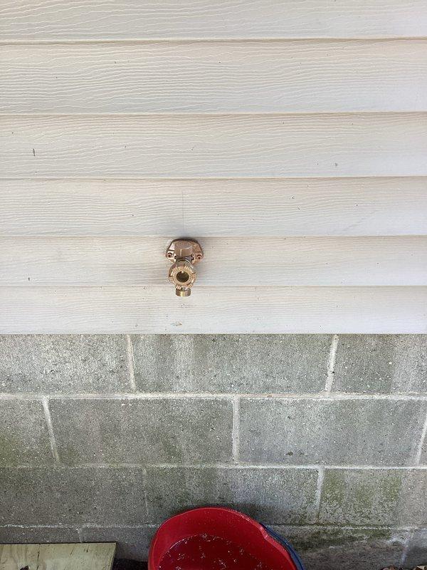 Responded to return service call for exterior hose bib that was previously repaired but had resumed leaking. Upon arrival, inspected the outdoor spigot mounted on the building's vinyl siding above the concrete block foundation. Identified failed seal or valve component causing water leakage. Removed and replaced faulty internal parts of the hose bib assembly. Tested the spigot under full water pressure to verify complete repair and confirm no further leaking. Repair completed successfully with proper function restored to the outdoor faucet.