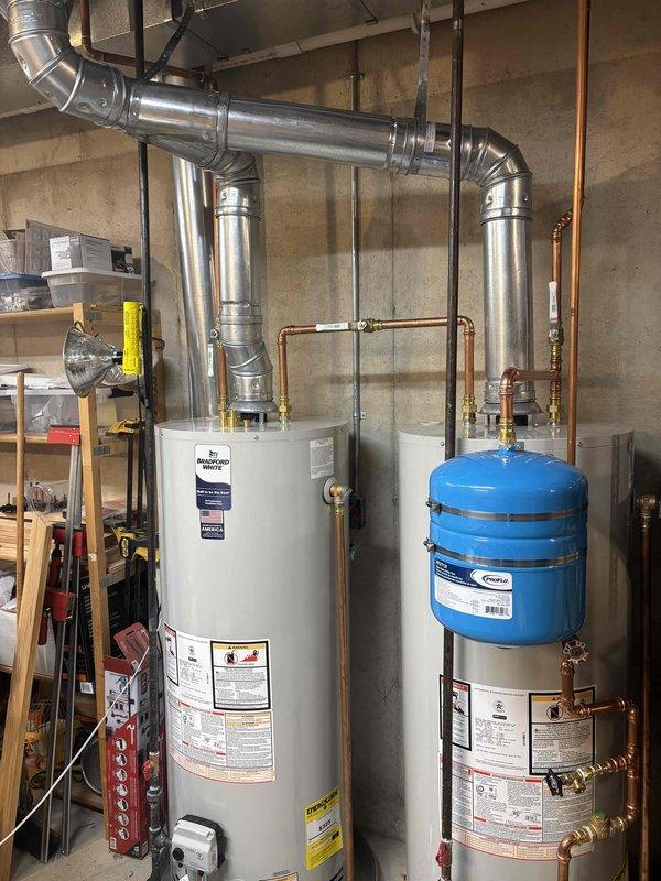 Responded to follow-up service call for recently installed water heater system to address venting concerns. Upon inspection, identified minor adjustments needed to the metallic ductwork configuration above the water heater installation. Modified venting elbows and joints to ensure proper draft and compliance with manufacturer specifications. Verified all duct connections were properly secured with metal straps to ceiling joists and confirmed adequate clearances from combustible materials. Tested system operation to ensure proper exhaust ventilation and verified no backdraft conditions present. All plumbing connections, including copper piping to blue expansion tank and associated brass valves, remained secure and operational throughout the adjustment process.
