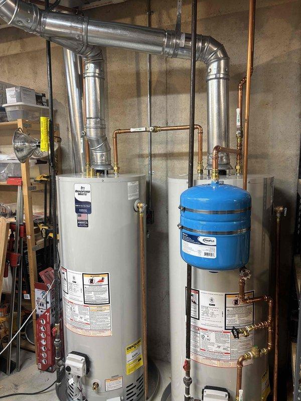 Responded to follow-up service call for recently installed water heater system to address venting concerns. Upon inspection, identified minor adjustments needed to the metallic ductwork configuration above the water heater installation. Modified venting elbows and joints to ensure proper draft and compliance with manufacturer specifications. Verified all duct connections were properly secured with metal straps to ceiling joists and confirmed adequate clearances from combustible materials. Tested system operation to ensure proper exhaust ventilation and verified no backdraft conditions present. All plumbing connections, including copper piping to blue expansion tank and associated brass valves, remained secure and operational throughout the adjustment process.