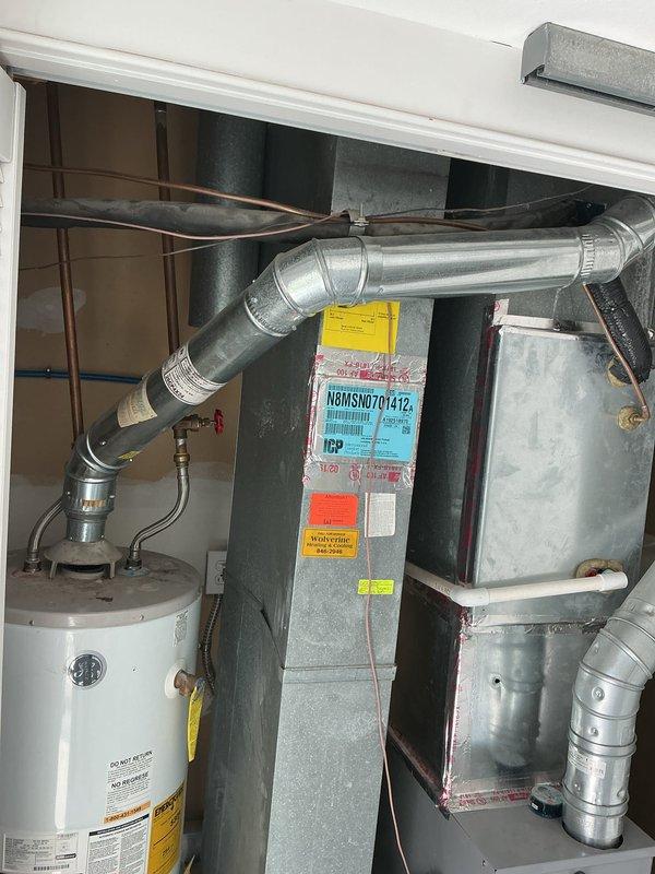 Responded to service call for water heater leaking from bottom. Upon inspection, found 10-year-old residential water heater with visible water accumulation at base of unit. Assessed condition of water heater and surrounding HVAC equipment in mechanical closet. Documented equipment setup including water heater, air handler unit, refrigerant lines, and ductwork configuration. Due to age of unit and location of leak at bottom of tank, determined water heater requires replacement as tank leaks are not repairable. Photographed installation area and equipment for replacement planning purposes.