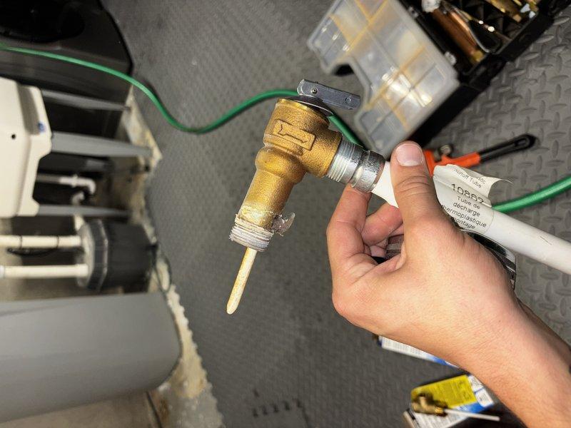 Responded to water leak on 9-year-old Bradford White water heater. Identified failed temperature and pressure relief valve as source of leak, evidenced by corrosion and water staining on surrounding concrete surfaces. Removed defective T&P relief valve and replaced with new brass valve, restoring proper operation and eliminating active leak.