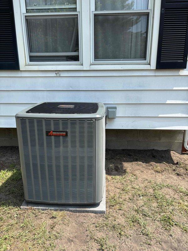 Successfully completed full air conditioning system replacement at residential property. Removed existing outdoor condenser unit and installed new AC condenser on exterior wall adjacent to white vinyl siding. New unit positioned on concrete pad at ground level with proper clearances maintained for optimal airflow and serviceability. 

Established electrical connections with new disconnect box mounted to exterior siding, ran electrical conduit and refrigerant lines from condenser to indoor air handler. Verified all refrigerant line connections properly brazed and pressure tested. System charged with appropriate refrigerant to manufacturer specifications. Completed final electrical connections, tested unit operation through full cooling cycle, and confirmed proper amperage draw and system pressures. All installation work performed in accordance with manufacturer guidelines and local code requirements. Unit operational and ready for service.