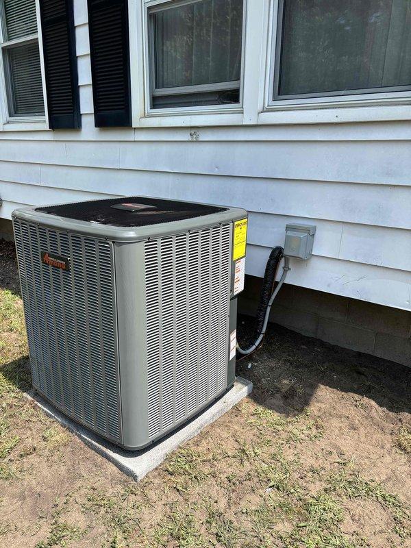 Successfully completed full air conditioning system replacement at residential property. Removed existing outdoor condenser unit and installed new AC condenser on exterior wall adjacent to white vinyl siding. New unit positioned on concrete pad at ground level with proper clearances maintained for optimal airflow and serviceability. 

Established electrical connections with new disconnect box mounted to exterior siding, ran electrical conduit and refrigerant lines from condenser to indoor air handler. Verified all refrigerant line connections properly brazed and pressure tested. System charged with appropriate refrigerant to manufacturer specifications. Completed final electrical connections, tested unit operation through full cooling cycle, and confirmed proper amperage draw and system pressures. All installation work performed in accordance with manufacturer guidelines and local code requirements. Unit operational and ready for service.