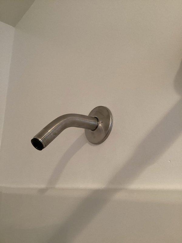 Responded to service call for shower arm escutcheon plate installation that was left off during previous repair. Upon arrival, found exposed shower arm with threading visible and no decorative cover plate installed. Successfully installed brushed nickel escutcheon plate flush against wall, covering the wall penetration and completing the shower fixture assembly. Verified proper fit and alignment of cover plate with existing dual-head shower system. Installation restored finished appearance to shower stall.