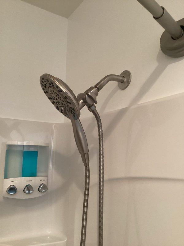 Responded to service call for shower arm escutcheon plate installation that was left off during previous repair. Upon arrival, found exposed shower arm with threading visible and no decorative cover plate installed. Successfully installed brushed nickel escutcheon plate flush against wall, covering the wall penetration and completing the shower fixture assembly. Verified proper fit and alignment of cover plate with existing dual-head shower system. Installation restored finished appearance to shower stall.