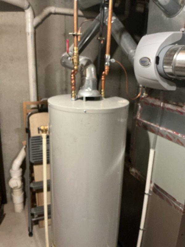 Conducted on-site assessment for exterior spigot plumbing project. Evaluated existing water heater installation and associated copper supply lines, compression fittings, and shut-off valves in mechanical room to determine connection points for proposed outdoor hose bib. Documented current plumbing configuration including PVC drainage system and HVAC ductwork proximity for routing considerations. Photographed utility space layout and access points to prepare comprehensive project estimate for exterior spigot installation with proper freeze protection and code-compliant materials.