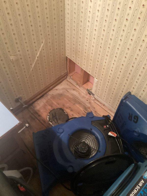 Completed installation of client-supplied faucet fixture. Upon arrival, discovered significant water damage to wall with visible moisture staining and discoloration extending from ceiling area. Removed damaged wallboard section to expose underlying structure and assess extent of water intrusion. Inspected copper supply lines and plumbing connections in affected area. Deployed industrial air mover to facilitate drying of moisture-damaged wall cavity and surrounding materials. Installed new faucet fixture per manufacturer specifications and tested all connections for proper operation and leak-free performance.