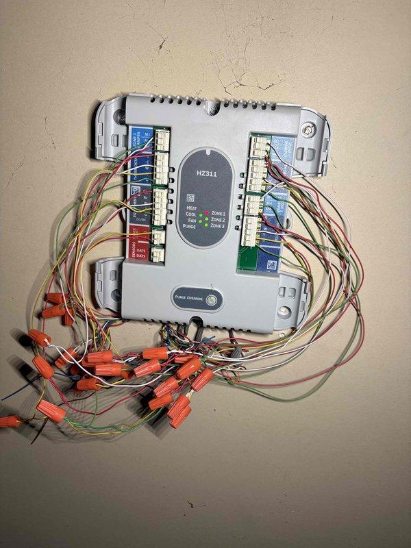 Responded to no cooling complaint for upstairs zone on 8-year-old Rheem system. Upon arrival, found thermostat and HZ311 zone control panel with exposed wiring requiring attention. Inspected multi-zone HVAC system, verified thermostat communication with zone controller, checked all wire terminations at control board terminals, and assessed system operation across all three zones. Addressed wiring concerns, secured connections, and restored proper cooling operation to affected upstairs zone.