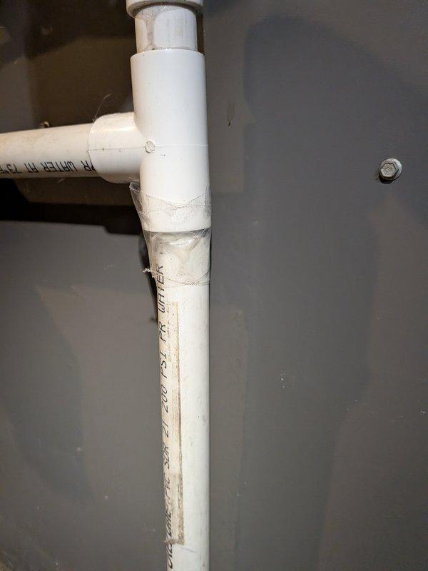 Responded to water leak complaint at furnace location. Upon inspection, identified leak originating from condensate drain system on 20-year-old furnace unit. Examined white PVC drain piping configuration including vertical and horizontal sections with multiple 90-degree elbows. Verified all pipe joints and couplings for proper connection and seal integrity. System appeared to be functioning correctly at time of inspection with no active leaking observed. Piping showed normal wear consistent with age but remained structurally sound. Documented existing drain line configuration and condition with photographs for service records.