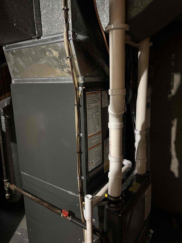 Completed full HVAC system replacement including outdoor condensing unit and indoor furnace assembly. Installed new gray cabinet furnace with proper PVC intake and exhaust venting configuration in mechanical room. Connected metallic supply ductwork and copper refrigerant lines with isolation valve. Mounted outdoor condensing unit on existing concrete pad with proper clearances from structure. Installed electrical disconnect box on exterior wall and ran conduit from house to unit. Verified all refrigerant line connections, electrical wiring, and condensate drainage. System tested and operational upon completion.