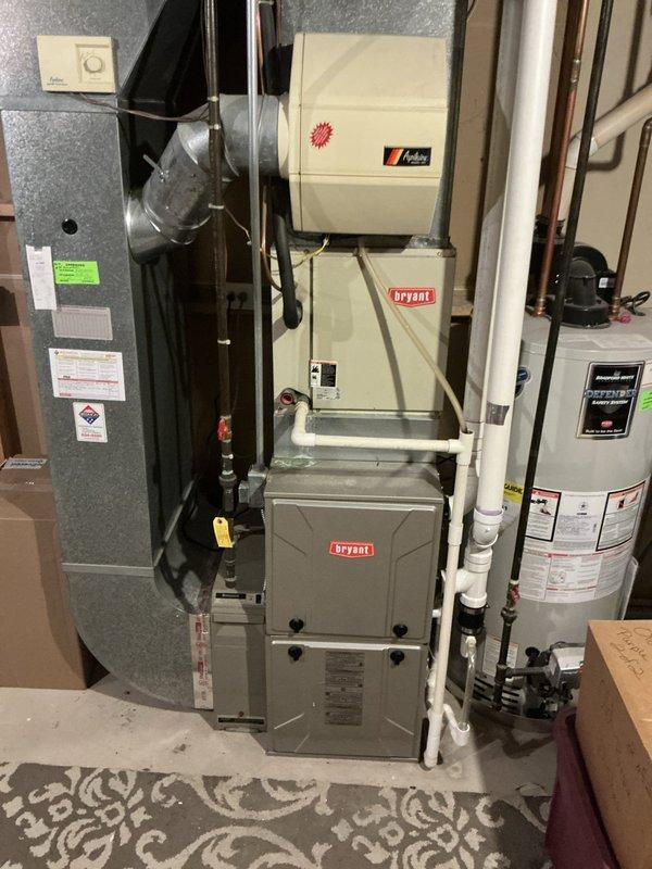 Completed comprehensive AC estimate for 16-year-old residential cooling system. Documented existing HVAC infrastructure including basement air handler, Bryant furnace with humidifier, water heater, and exterior condenser unit showing signs of age and weathering. Photographed complete system layout, ductwork connections, refrigerant line routing, electrical service components, and outdoor equipment placement for replacement proposal assessment.