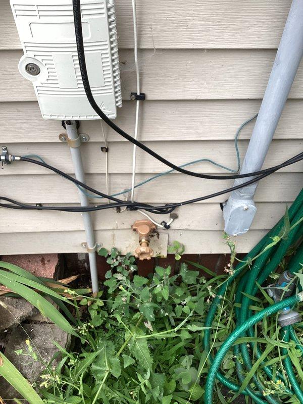 Responded to service call for exterior spigot inspection. Evaluated multiple outdoor hose bibs and water supply connections mounted on building exterior, including brass fittings with temporary wrapping material. Documented condition of plumbing fixtures, associated piping, and connections for maintenance records. Noted vegetation growth around foundation area near water supply lines that may require future access considerations.