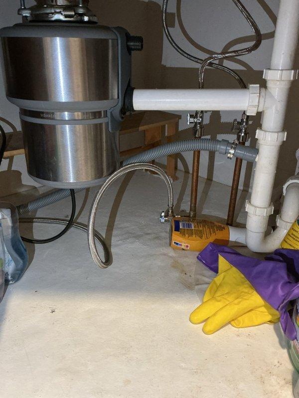 Responded to no water call where homeowner had shut off main water supply due to active leak. Upon arrival, performed comprehensive inspection of plumbing system to locate source of water loss. Examined under-sink plumbing configuration including garbage disposal unit, PVC drainage pipes, and flexible supply lines. Inspected water heater area and associated copper piping connections. Identified leak location and assessed extent of damage. Utilized diagnostic equipment to verify system integrity. Documented conditions with photos showing affected areas including disposal installation, supply lines, and water heater connections with drain pan. Provided customer with findings and recommendations for necessary repairs to restore water service safely.