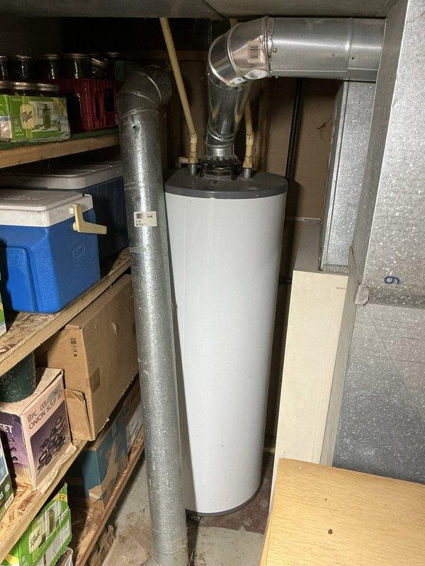 Conducted on-site estimate for furnace and water heater replacement in residential property. Assessed existing approximately 50-year-old furnace system and aging water heater located in basement utility area. Documented current equipment conditions including Lennox brand HVAC unit with existing galvanized metal ductwork, return air plenum, and white cylindrical water heater with top-mounted flue connections. Photographed mechanical room layout, existing duct configurations, and equipment placement to develop accurate replacement proposal. Evaluated structural considerations including exposed ceiling insulation, wooden support beams, and available clearances for new equipment installation.